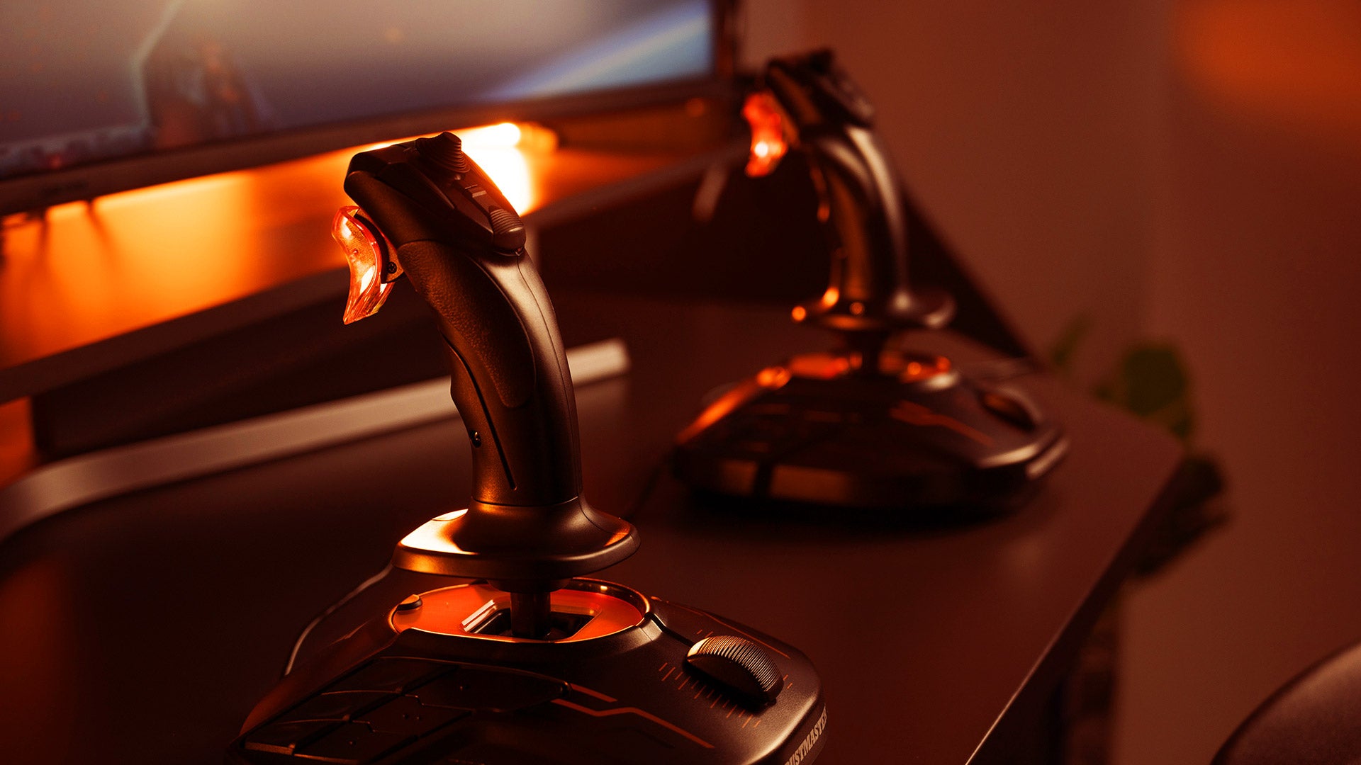 T.16000M FCS Space Sim Duo joysticks on a desk in warm light